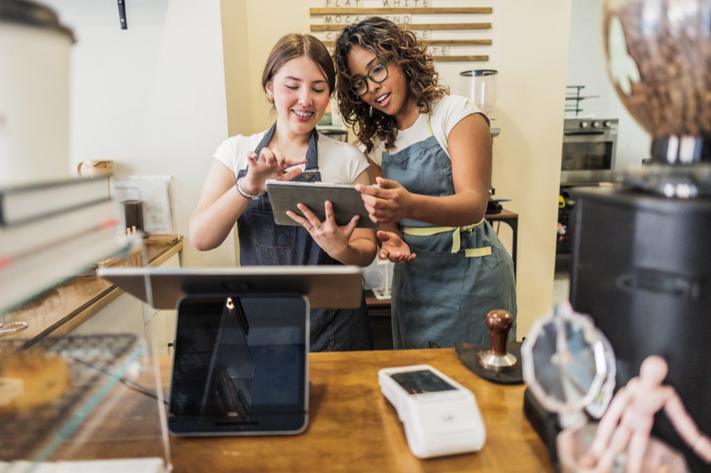 small-business-local-seo-and-marketing - Moxie Creative Solutions - Moxie Creative Solutions Cafe employees in aprons managing business operations and order management on a tablet at the front register.